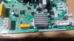Close-up of a green PCB with a heatsink, capacitors, and white connectors on a wooden surface.