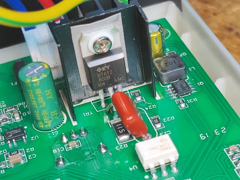Inside of a Soldering Station with BTA12 Chip Close-up of the inside of a soldering station with a BTA12 chip and capacitors on a green PCB.