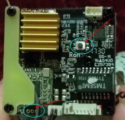 Płyta elektroniczna z zaznaczonym przyciskiem resetu oznaczonym strzałką.