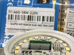 Close-up of an LED bulb with an integrated circuit labeled CB2L, with a product packaging label for TY-A60-18W-220V in the background.