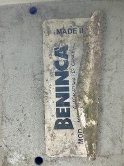Sfotografowana część naklejki na siłowniku Beninca, częściowo zawinięta i nieczytelna.