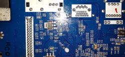 Zbliżenie na niebieską płytkę PCB z widocznymi ścieżkami i komponentami elektronicznymi.