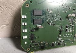 Zbliżenie na płytkę drukowaną z widocznymi układami scalonymi i elementami elektronicznymi.