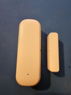 AUBESS Door Sensor – Two Components Two white components of an AUBESS door sensor on a blue background.