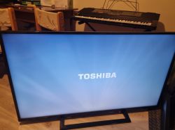 Toshiba TV with logo on screen and keyboard in the background.