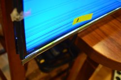Zbliżenie na uszkodzoną krawędź telewizora Samsung z widocznymi zakłóceniami na ekranie.