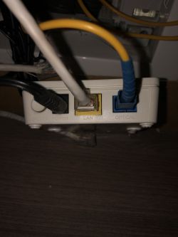 Biały panel z portami oznaczonymi jako POWER, LAN i OPTICAL z podłączonymi kablami.