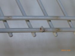 Zbliżenie na zardzewiałe miejsce na metalowym koszu zmywarki.