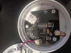 View of the interior of a smoke detector with electronic circuitry and pins on the printed circuit board.