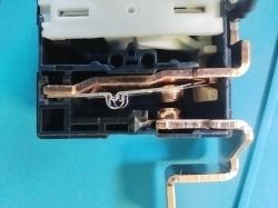 Interior of an electrical switch with visible metal components on a blue surface.
