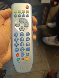 Osoba trzymająca uniwersalny pilot Philips SRP3004/53.