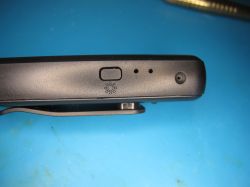 Top edge of device with button and microphone openings Close-up of top edge of black electronic device with button and microphone holes
