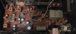 Wnętrze starego urządzenia elektronicznego z widoczną płytką drukowaną i komponentami