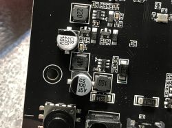 Close-up of electronic components on a black PCB with CS-labeled capacitors.