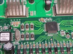 Zbliżenie na płytę główną starego switcha sieciowego z widocznymi układami scalonymi i elementami elektronicznymi.