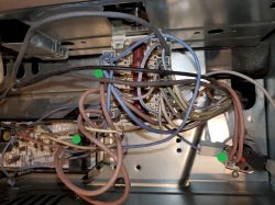 Widok wnętrza urządzenia elektronicznego z licznymi przewodami i elementami podzespołów.