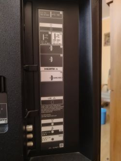 Panel boczny telewizora z różnymi wejściami, w tym HDMI, USB i LAN.