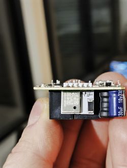 Close-up of electronic module with capacitor and chip bearing QR code