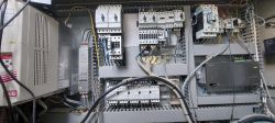 Wnętrze szafy sterowniczej frezarki z widocznymi elementami elektrycznymi i kablami.