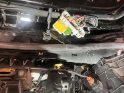 Zbliżenie na złącze elektryczne i wiązkę przewodów w samochodzie przy słupku drzwi.