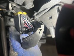 Zbliżenie na 10-pinową kostkę lampy w samochodzie Volvo FH, widoczne różnokolorowe przewody.