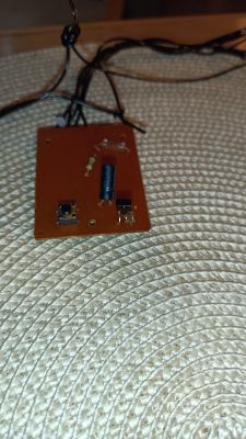 Zbliżenie na prostą płytkę PCB z kondensatorem, rezystorem i przyciskami.