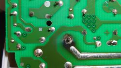 Uszkodzona ścieżka lutownicza na zielonej płytce PCB z przypaleniem wokół pinu