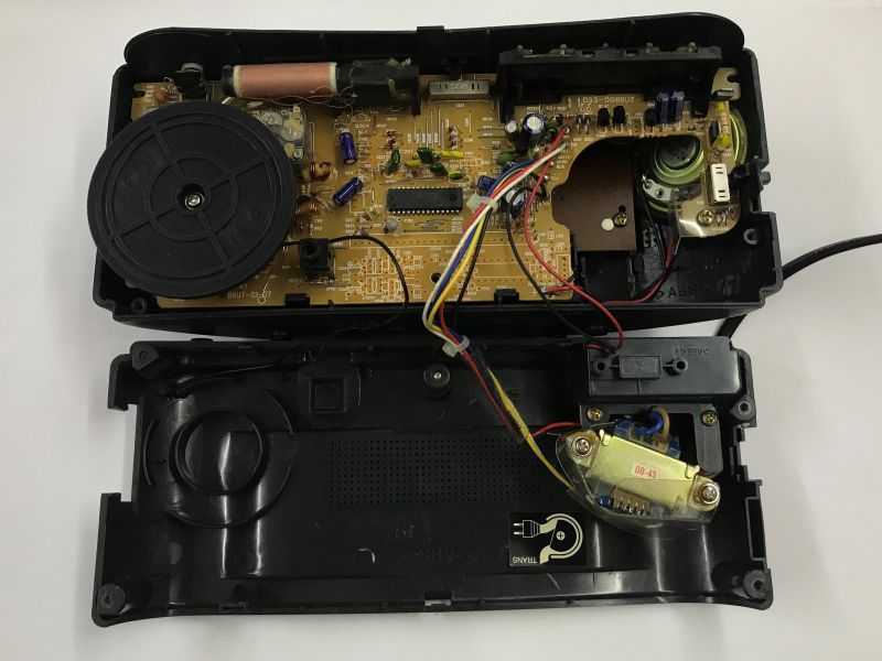 Wnętrze otwartego radiobudzika z widoczną płytką PCB i transformatorami