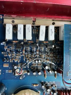 Zbliżenie na płytkę drukowaną wzmacniacza z widocznymi komponentami elektronicznymi.