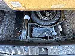Image of a car trunk compartment with a spare wheel and tools.