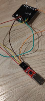 USB to TTL converter connected to a black electronic board with jumper wires