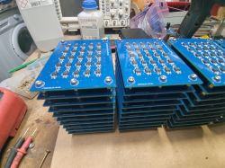 Stack of printed circuit boards with electronic components on a workshop table.