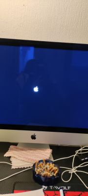 iMac screen with Apple logo on dark background.