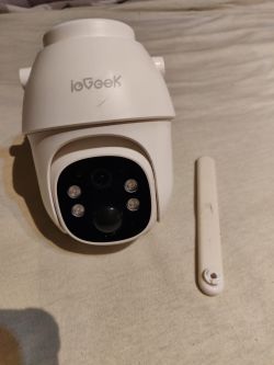Uszkodzona kamera ieGeek z urwaną anteną GSM leżącą obok na jasnym materiale