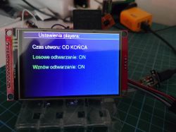 LCD screen showing “Player settings” menu on a red circuit board on a workbench