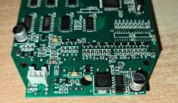 Zbliżenie na zieloną płytkę PCB z elementami elektronicznymi i oznaczeniami komponentów.