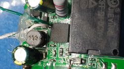 Close-up of a repaired circuit board using glue and wires.