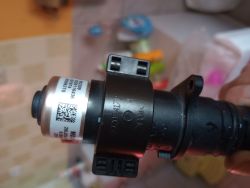 Czarny zawór elektromagnetyczny z etykietą i kodem QR trzymany w ręce