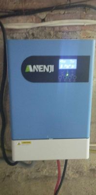 Niebieski falownik z logo Anenji zamontowany na ścianie.