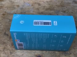 Blue packaging of Sonoff POWR316D energy meter on a wooden surface.