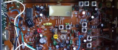 Widok wnętrza urządzenia elektronicznego z widocznym układem scalonym i różnymi elementami, takimi jak kondensatory i rezystory.