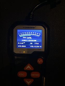 Tester akumulatora KONNWEI z wynikiem SOC 54% i napięciem 12,23 V na podświetlanym ekranie.
