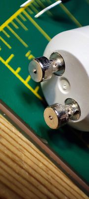 Close-up of GU10 Bulb Pins Two metal pins of a GU10 bulb on a green pad with a ruler.