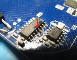 Close-up of a circuit board with a highlighted chip marked by a red arrow.
