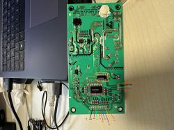 Printed circuit board with pin labels next to a laptop.