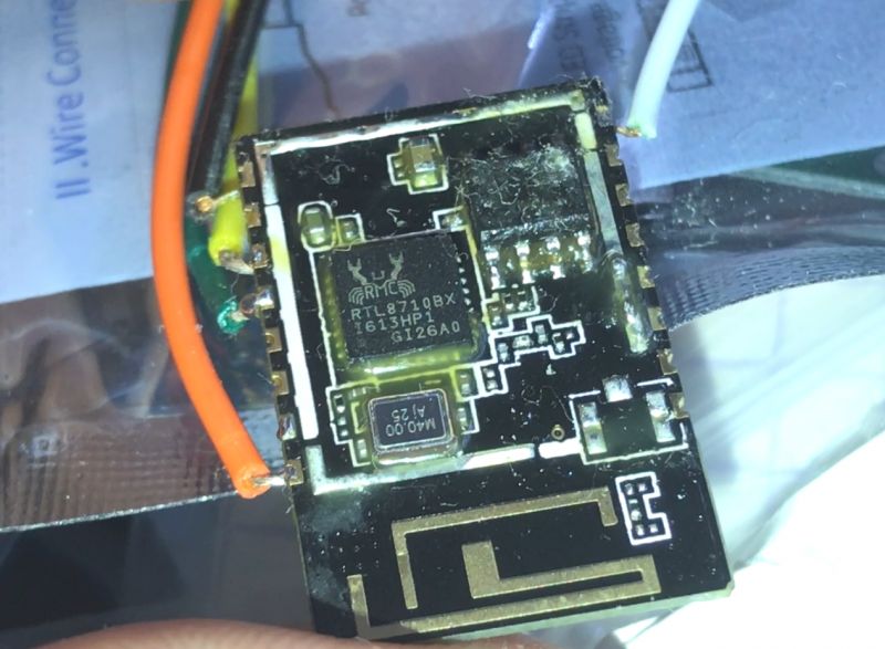 Close-up of a microchip labeled RTL8710BX with soldered wires.