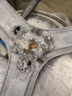 Silnie skorodowany element metalowy w pralce z widocznymi ubytkami i korozją