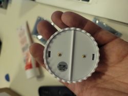 A person holding a round white plastic component with WIFI BT QC6 label.