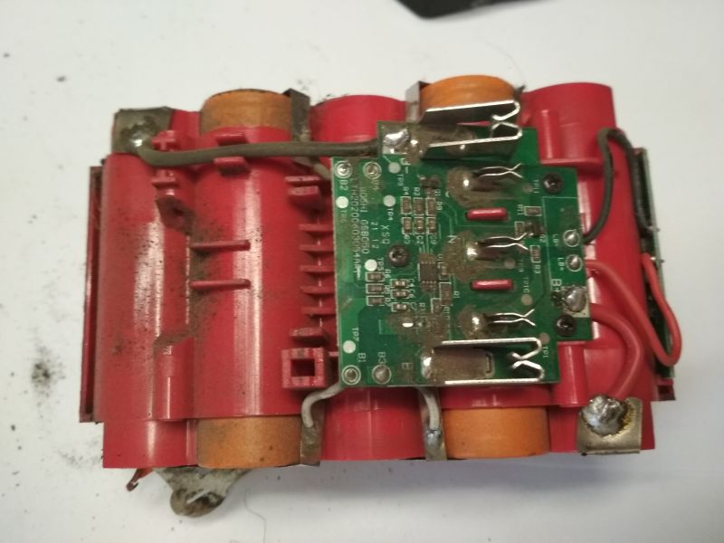 Wnętrze akumulatora Megatto 18V; widoczne ogniwa cylindryczne i płytka PCB z lekkimi zabrudzeniami.