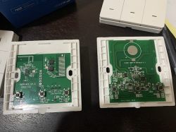 Disassembled Electronic Modules with Circuit Boards The image shows two disassembled electronic modules on white casings with visible green printed circuit boards and various electronic components.